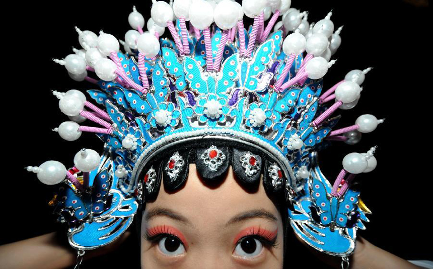 Zhang Xinwen wears Opera headwear at Dongmen drama stage in Liuzhou City, southwest China's Guangxi Zhuang Autonomous Region, Nov. 4, 2011. As an 11-year-old pupil of Liuzhou Primary School, Zhang Xinwen has been studying Peking Opera for over three years. She fell for the charm of Peking Opera by chance and became a diligent opera fan at the age of eight. Now she dreams of being an Peking Opera actress on a bigger stage.