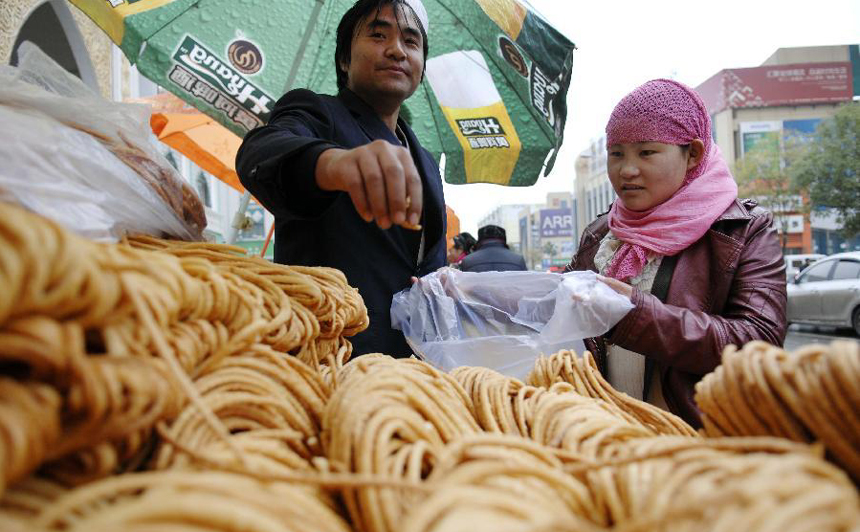 A muslim (R) buys Sanzi, or deep-fried dough twists, in Yinchuan, capital of Ningxia Hui Autonomous Region, Nov.6, 2011. Muslims in northwest China celebrated their traditional feast of Corban Festival, or Eid al-Adha Sunday.