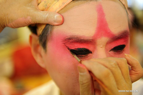 A Peking Opera fan has the make-up applied backstage before a performance in Wuhan, central China's Hubei Province, Nov. 4, 2011. Dozens of Peking Opera fans from China and abroad held a show during the ongoing sixth Peking Opera Festival here Friday.