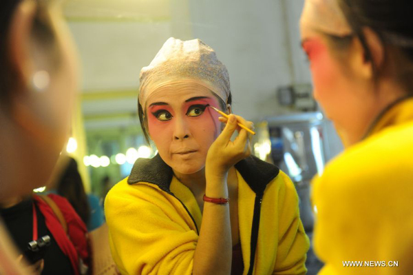 A Japanese amateur Peking Opera actress applies make-up backstage before a performance in Wuhan, central China's Hubei Province, Nov. 4, 2011. Dozens of Peking Opera fans from China and abroad held a show during the ongoing sixth Peking Opera Festival here Friday. 