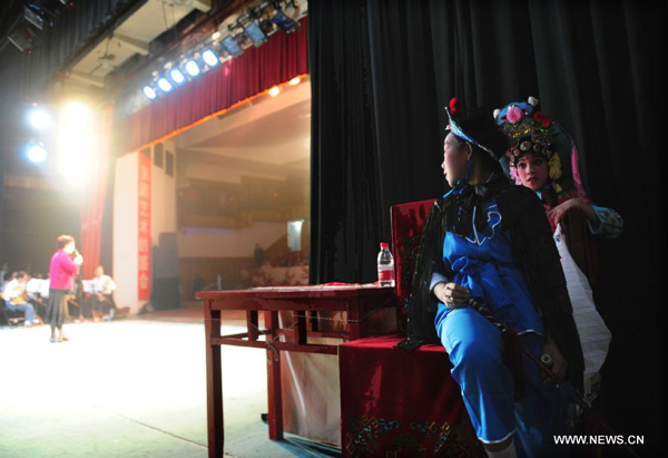 Teenage Peking Opera fans Zhi Xuelian and Fan Beibei (Front) watch a performance behind the curtain in Wuhan, central China's Hubei Province, Nov. 4, 2011. Dozens of Peking Opera fans from China and abroad held a show during the ongoing sixth Peking Opera Festival here Friday. 