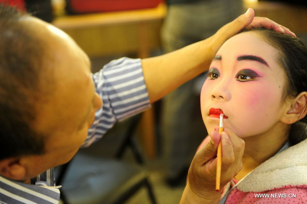 Fan Beibei (R), a ten-year-old amateur Peking Opera actress, has the make-up applied backstage before a performance in Wuhan, central China's Hubei Province, Nov. 4, 2011. Dozens of Peking Opera fans from China and abroad held a show during the ongoing sixth Peking Opera Festival here Friday. 