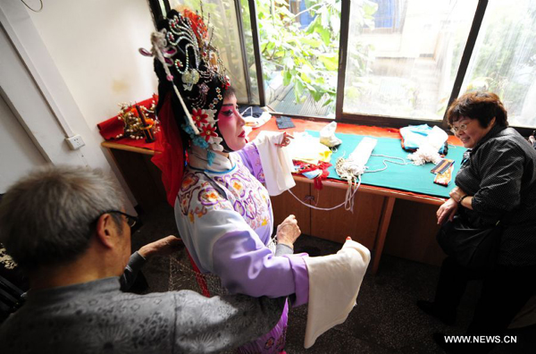 Amateur Peking Opera actress Wang Jun puts on a costume backstage before a performance in Wuhan, central China's Hubei Province, Nov. 4, 2011. Dozens of Peking Opera fans from China and abroad held a show during the ongoing sixth Peking Opera Festival here Friday. 