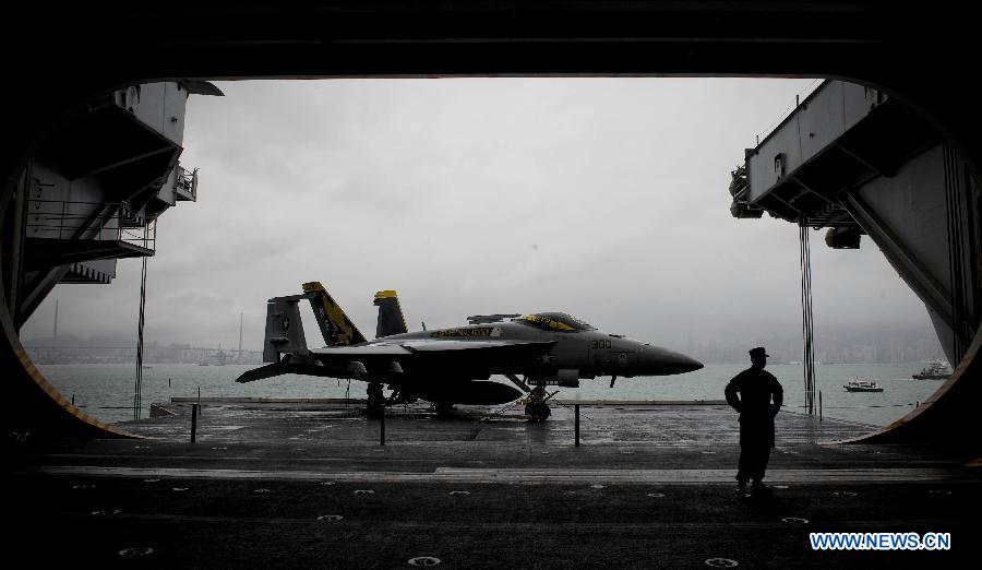 A U.S. naval soldier stands next to a fighter plane on board U.S. aircraft carrier USS George Washington in Hong Kong, south China, Nov. 9, 2011. The U.S. nuclear powered aircraft carrier USS George Washington pulled in Hong Kong waters on Wednesday to get replenishment upon her second portal call to the city. [Lui Siu Wai/Xinhua]