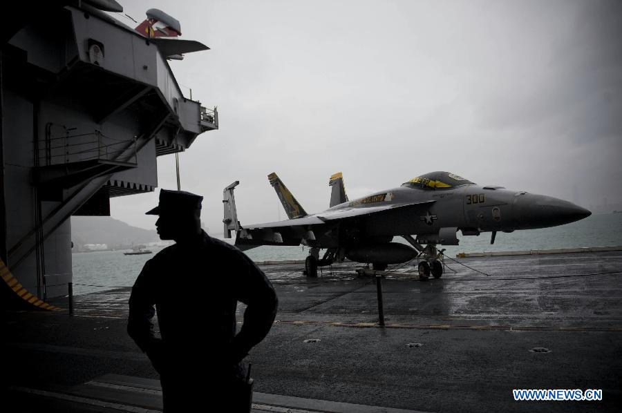 A U.S. naval soldier stands next to a fighter plane on board U.S. aircraft carrier USS George Washington in Hong Kong, south China, Nov. 9, 2011. The U.S. nuclear powered aircraft carrier USS George Washington pulled in Hong Kong waters on Wednesday to get replenishment upon her second portal call to the city. [Lui Siu Wai/Xinhua] 