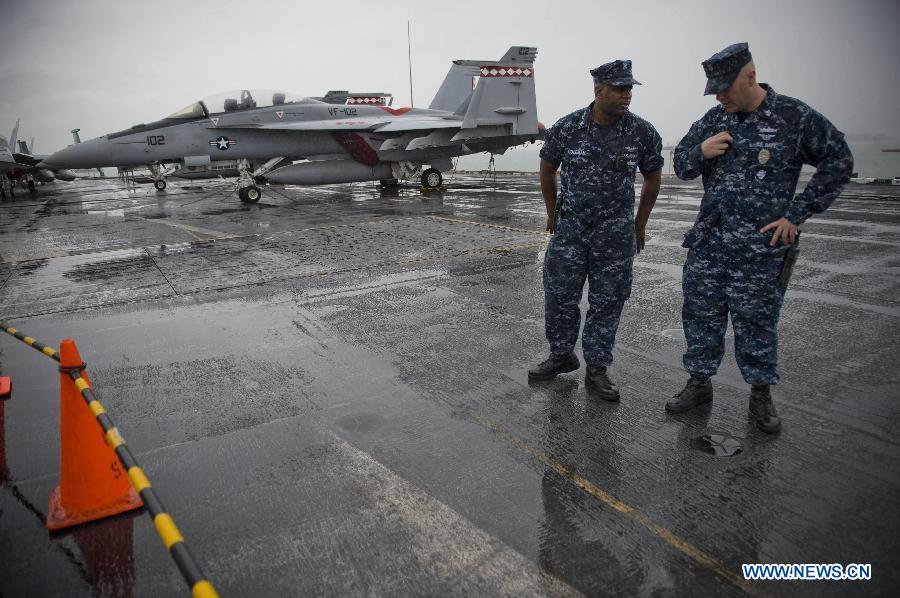 Two U.S. naval soldiers stand next to a fighter plane on board U.S. aircraft carrier USS George Washington in Hong Kong, south China, Nov. 9, 2011. The U.S. nuclear powered aircraft carrier USS George Washington pulled in Hong Kong waters on Wednesday to get replenishment upon her second portal call to the city. [Lui Siu Wai/Xinhua]