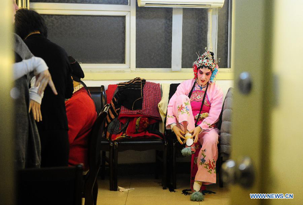 Stephanie Willing, a member of Qi Shufang Peking Opera Troupe, wears embroidery shoes at backstage before the performance during the 6th China Peking Opera Art Festival in Wuhan City, capital of central China's Hubei Province, Nov. 8, 2011. 