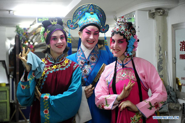 Stephanie Willing (R), Lauren Engleman (C) and April Aubert, members of Qi Shufang Peking Opera Troupe, pose for photos at backstage during the 6th China Peking Opera Art Festival in Wuhan City, capital of central China's Hubei Province, Nov. 8, 2011.