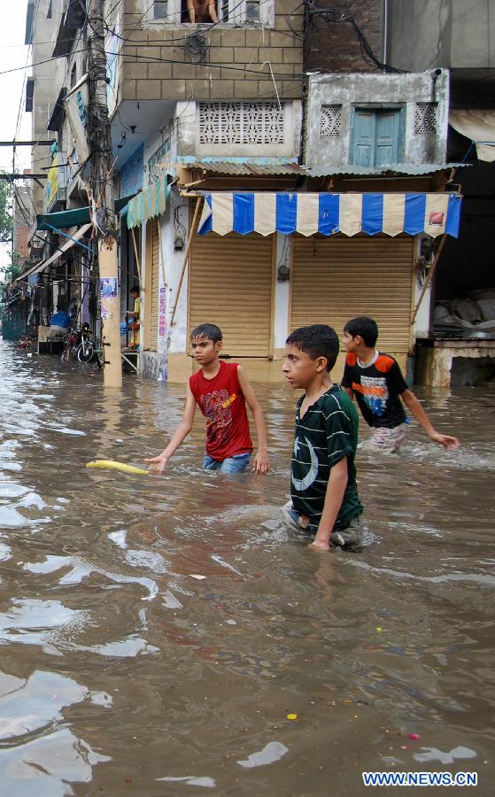 Pakistani children play in a flooded street after heavy rainfall in eastern Pakistan's Lahore on Nov. 10, 2011. According to the Meteorological Office, cold wave would continue for two to three days, which would drop the temperature further in Lahore.