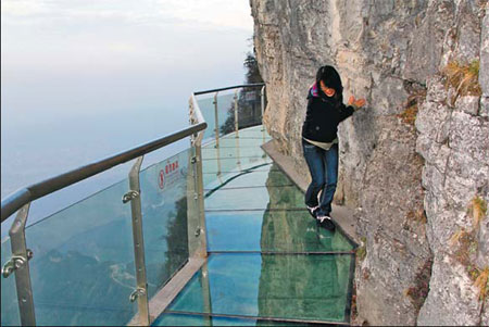 A tourist gingerly makes her way on a glass skywalk built along the cliffs of Tianmen Mountain, Zhangjiajie, Hunan province, on Wednesday. [Photo/China Daily]