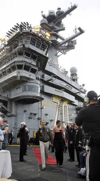 President Barack Obama salutes as he and first lady Michelle Obama walk on the flight deck of the USS Carl Vinson for the Carrier Classic NCAA college basketball game between Michigan State and North Carolina on Friday, Nov. 11, 2011, in Coronado, Calif.