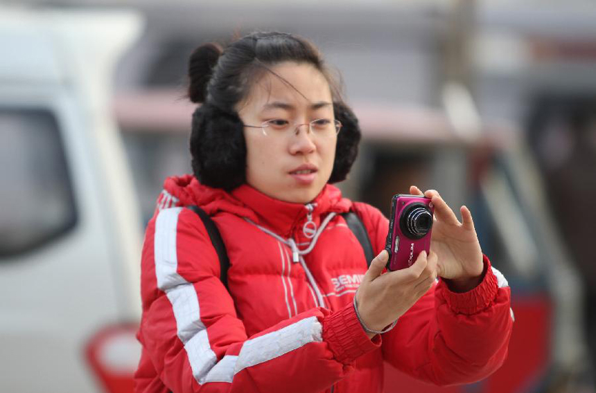 A girl wearing warm clothes takes photos in Harbin, capital of northeast China's Heilongjiang Province, Nov. 13, 2011. The temperature in Heilongjiang has dropped by a large margin from Saturday.