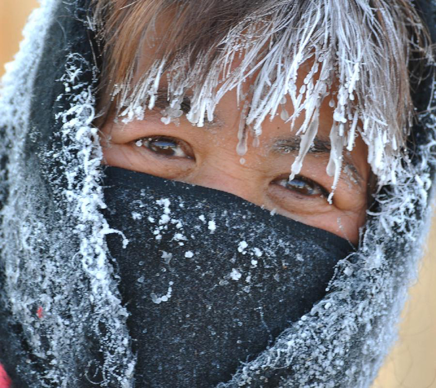 Photo taken on Nov. 13, 2011 shows a woman whose head is covered with ice and snow in Deerbuer Township of Hulunbuir City, north China's Inner Mongolia Autonomous Region. The temperature here has plummeted to 30 degrees below zero centigrade. 