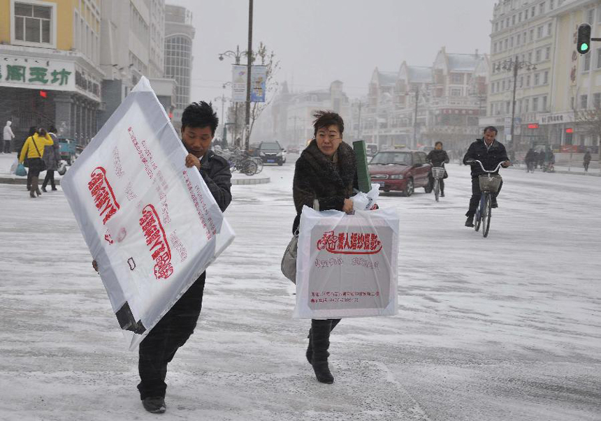 Passengers walk hard amid snow and wind in Deerbuer Township of Hulunbuir City, north China's Inner Mongolia Autonomous Region, Nov. 13, 2011. The temperature here has plummeted to 30 degrees below zero centigrade.