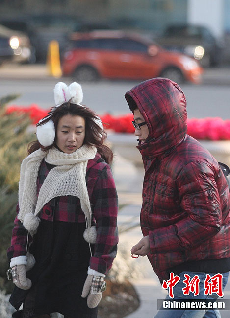 People wrapped in warm clothes walk in a street in Harbin, capital of northeast China's Heilongjiang Province, Nov. 13, 2011. The temperature in Heilongjiang has dropped by a large margin from Saturday. 