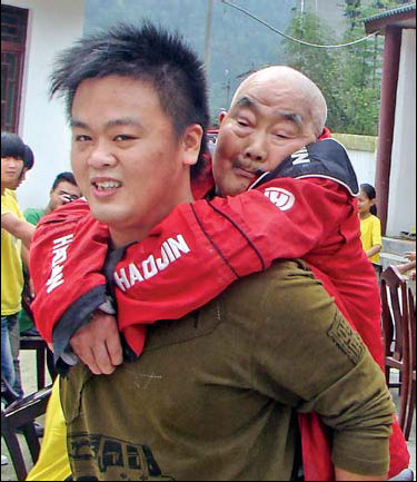 Volunteer Zhou Xuanci helps an elderly man following the 2008 earthquake in Anxian county, Sichuan province. 