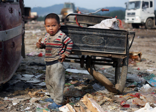 A boy eats a chicken leg he found in a garbage landfill in Guiyang, capital of Southwest China's Guizhou province on Sept 18. Like him, many children in rural China cannot afford to go to a kindergarten. [Photo/China Daily]