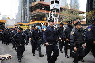 Police stand guard as Occupy Wall Street protesters demonstrate near Zuccotti Park in New York City, the United States, Nov. 15, 2011. New York police cleared up Zuccotti Park early Tuesday after Occupy Wall Street protesters encamped for two months, and arrested around 200 protesters for resisting orders. [Deng Jian/Xinhua]