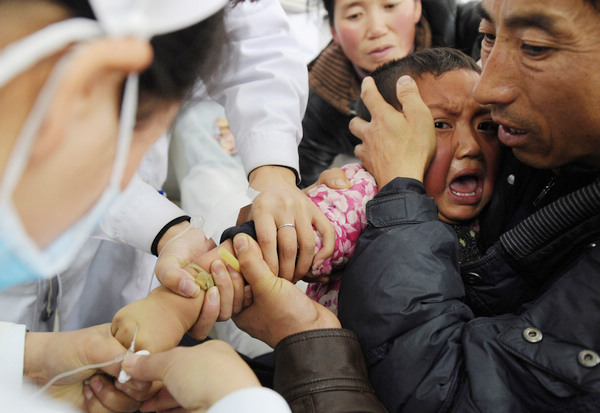 A little girl who was injured in the collision in Yulinzi township, Gansu province, cries as nurses at the Zhengning People's Hospital hook up her to an intravenous drip on Thursday. [China Daily] 