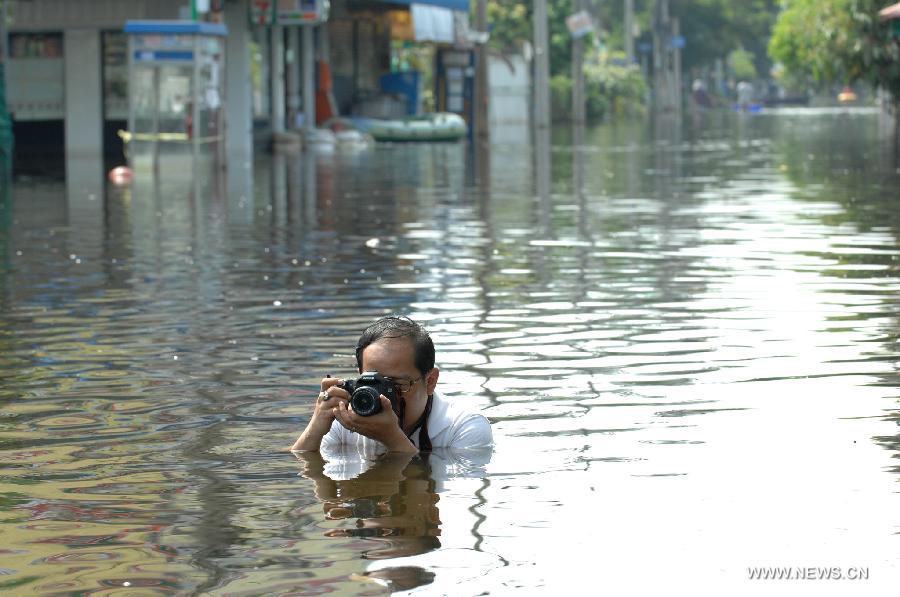 A man takes pictures in the floodwaters in Bang Khun Thian district in Bangkok, Thailand, Nov. 18, 2011. A total of 595 people were confirmed dead and two people were still missing in the floods that have inundated many provinces for more than three months, Thai Disaster Prevention and Mitigation Department reported on Friday. [Rachen Sageamsak/Xinhua]