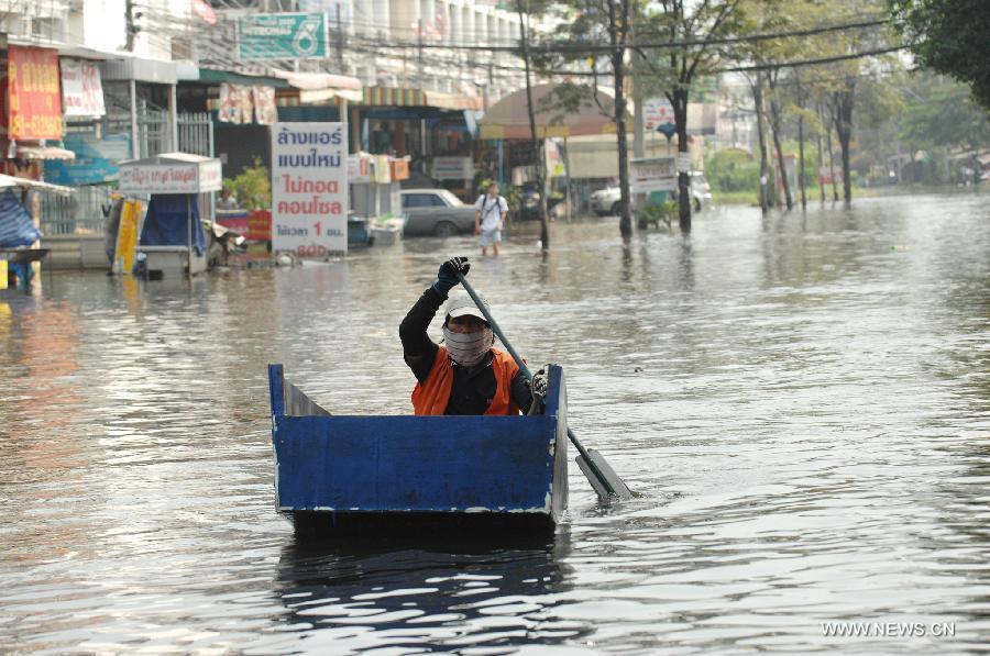 People row a boat in the floodwaters in Bang Khun Thian district in Bangkok, Thailand, Nov. 18, 2011. A total of 595 people were confirmed dead and two people were still missing in the floods that have inundated many provinces for more than three months, Thai Disaster Prevention and Mitigation Department reported on Friday. [Rachen Sageamsak/Xinhua]