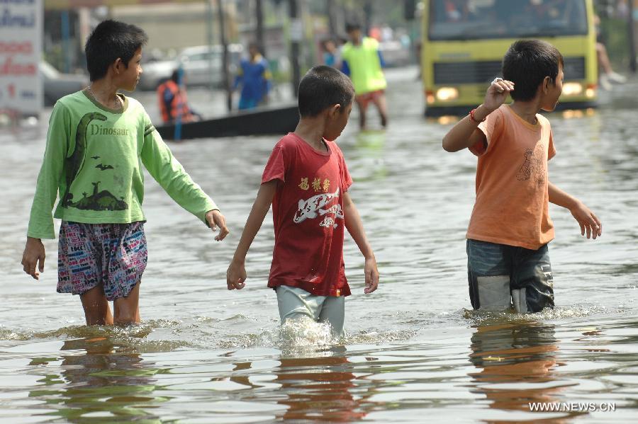 People walk in the floodwaters in Bang Khun Thian district in Bangkok, Thailand, Nov. 18, 2011. A total of 595 people were confirmed dead and two people were still missing in the floods that have inundated many provinces for more than three months, Thai Disaster Prevention and Mitigation Department reported on Friday. [Rachen Sageamsak/Xinhua]