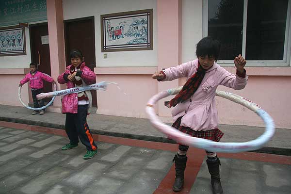 Three girls play hula-hoops together in a Cuncaoxin home for left-behind children in Wangjiang Village of Jintang County. [CnDG by Jiao Meng] 