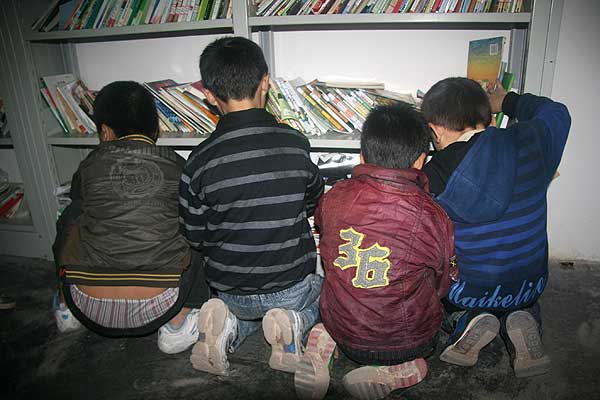 Four boys select books from shelves at a Cuncaoxin home. [CnDG by Jiao Meng]