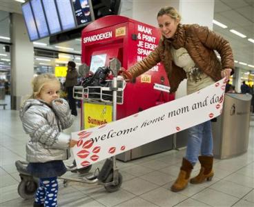 Two-year-old Luna (L) and her aunt hold a banner at Amsterdam Airport Schiphol November 24, 2011. [Agencies]