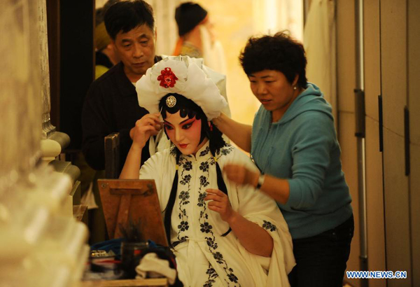 An artist of the Chinese Northern Kunqu Opera Theater makes up before the performance of the classic piece of Kunqu Opera 'Dou E Yuan' at the Austrian Academy of Sciences in Vienna, capital of Austria, Nov. 24, 2011. 