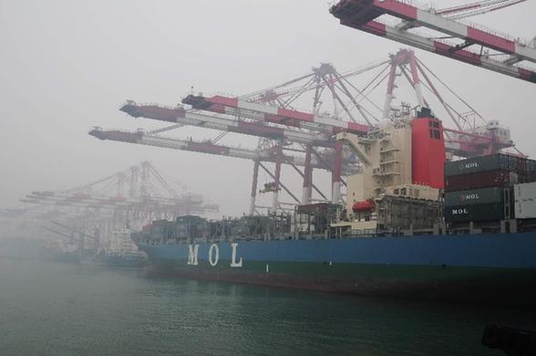 Container vessels anchor at the fog-shrouded Qingdao Port in east China's Shandong Province, Nov. 28, 2011. [Xinhua]