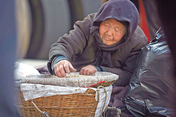 An elderly woman sells melon seeds and guavas in a shopping street in Lanzhou, capital of Northwest China's Gansu province, on Nov 10. Local media reported that the 83-year-old woman has to make a living by hawking even though she has five adult children, all of whom refuse to support her.[Photo/China Daily]