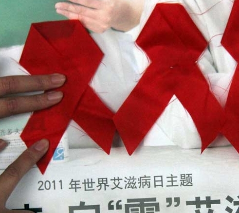 People stick red banners to a HIV prevention poster in Tancheng County, east China's Shandong Province, Nov. 29, 2011. Falling on Dec. 1, the World AIDS Day has its theme of 'Getting to Zero' this year. [Photo/Xinhua] 
