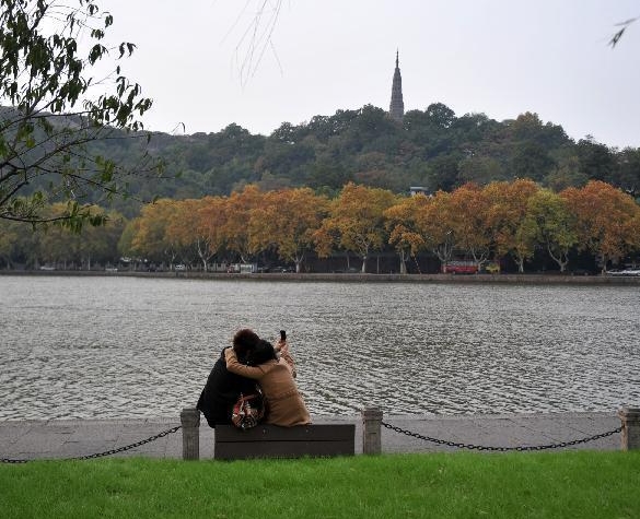 Tourists take photo of themselves with a cellphone by the West Lake in Hangzhou, east China's Zhejiang Province, Nov. 15, 2011. [Xinhua/Huang Zongzhi] 