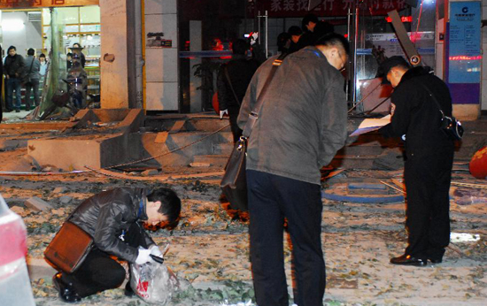 Police officers conduct an initial investigation at the site of an explosion in Wuhan, capital of central China's Hubei Province, Dec. 1, 2011.