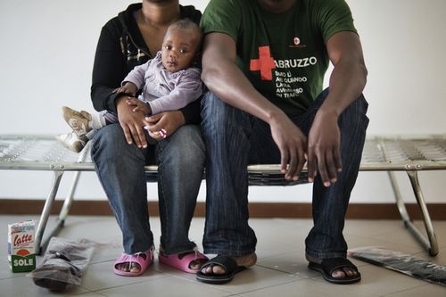 Portrait of a Nigerian family of asylum seekers posing on a bed also used as a couch in the living room of their home shared with other asylum seekers. MSF provides mental health support in Mineo reception centre, Italy, where some 2,000 asylum seekers of various nationalities have been transferred since March 2011. © Mattia Insolera 
