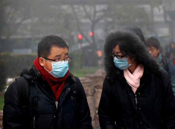 Two Beijing pedestrians wear masks as they walk on the street on Tuesday to protect them from the heavy smog.[Photo/ for China Daily]