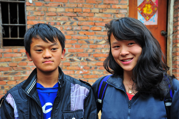 Zhou Yunlong (left) stands recently with Ming Foxweldon outside his home in Jiucheng village, Luxi county, the Honghe Hani and Yi autonomous prefecture in Yunnan province. 