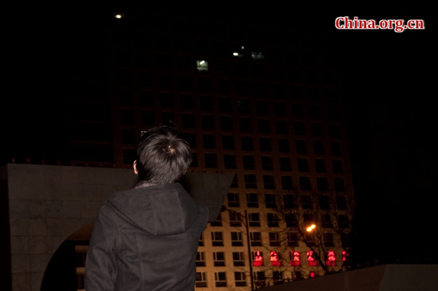 A student in Capital Normal University in Beijing trys to take photos of the half blocked moon with his mobile phone camera. [Pierre Chen / China.org.cn]