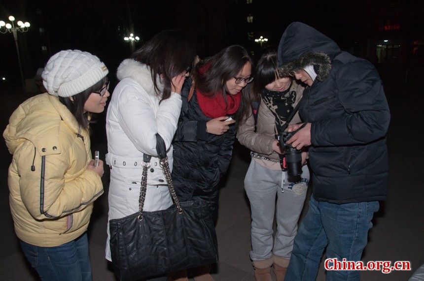 A group of stargazers are checking the images of lunar eclipse on one man&apos;s Nikon D90 camera. [Pierre Chen / China.org.cn]