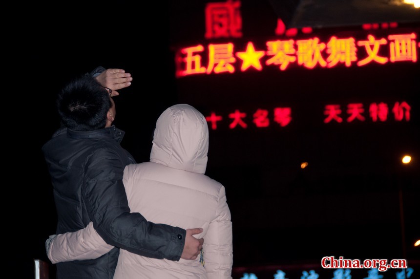 A couple on their way to a bus stop in Beijing stop to watch the progression of the total lunar eclipse. [Pierre Chen / China.org.cn]