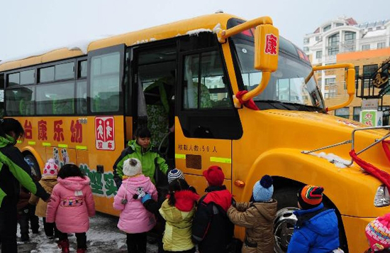 Children queue up to take on an American-style school bus of a kindergarten in Fushan District, Yantai City, east China's Shandong Province, Dec. 10, 2011. The Kangle Kindergarten in Yantai on Saturday put into use an American-style school bus, which is equipped with GPRS positioning system, stop signals, special seats for school children and other devices to ensure its safety. [Photo/Xinhua]