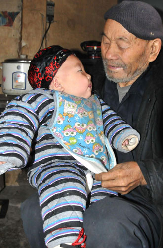 Yang holds his great-grandson at home, Dec 6, 2011. [Photo/Xinhua] 