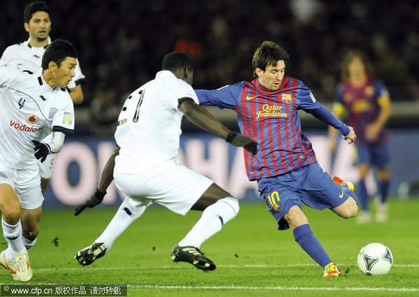 FC Barcelona striker Lionel Messi (R) shoots the ball past Al-Sadd SC captain Abdulla Koni (C) during the FIFA Club World Cup semi final match at Yokohama International Stadium in Yokohama, south of Tokyo, Japan, on Dec.15, 2011.