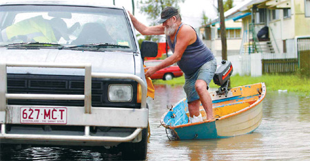 Australia: With one foot injured, a man makes it to his car so he can drive out of floodwaters at Depot Hill in Rockhampton, Queensland, on Jan 6. [Agencies]