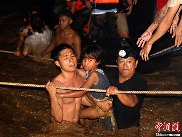 The volunteers are rescuing the residents in floods in Philippines on Dec. 17, 2011. Flash floods triggered by a tropical storm have killed hundreds in southern Philippine cities, and the disaster is becoming more seriously.