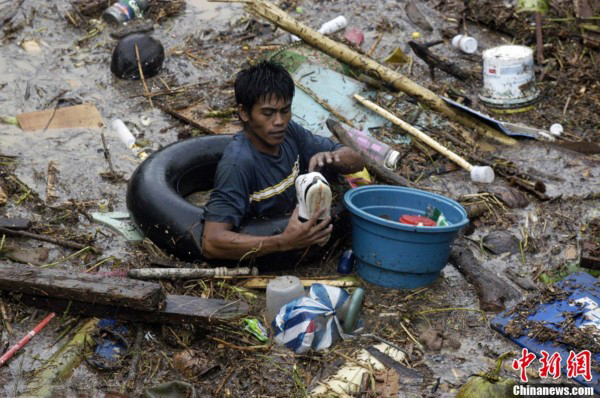 A man is trying to walk through the floods full of rubbishes in Philippines on Dec. 17, 2011. Flash floods triggered by a tropical storm have killed hundreds in southern Philippine cities, and the disaster is becoming more seriously.