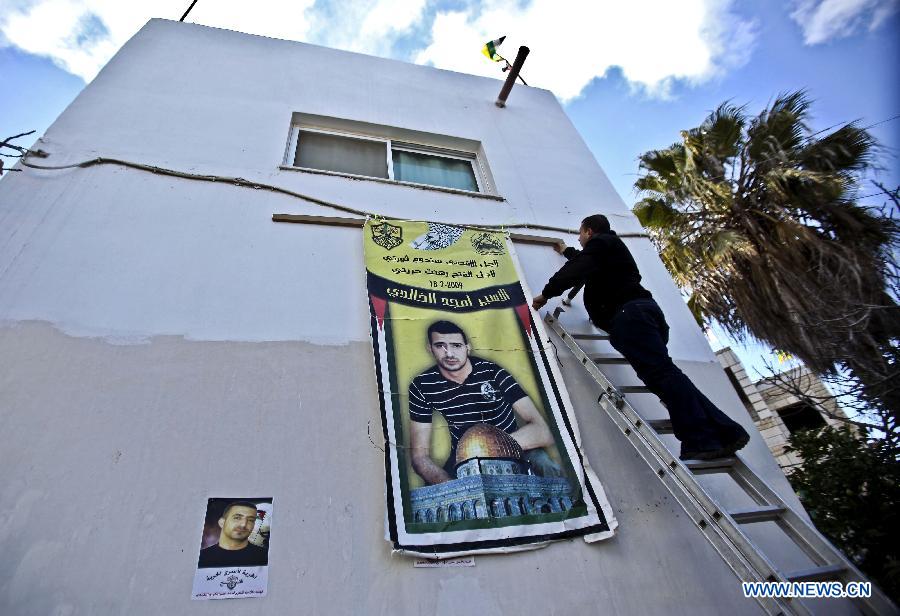 Brother of Palestinian prisoner Amjad Khaldi hangs his picture outside their house in the West Bank city of Ramallah, on Dec. 17, 2011. Amjad Khaldi is one of 550 Palestinian prisoners who will be freed on Sunday from Israeli jails, in the second phase of a deal reached with the Islamic Hamas movement in October to free Israeli soldier Gilad Shalit. 