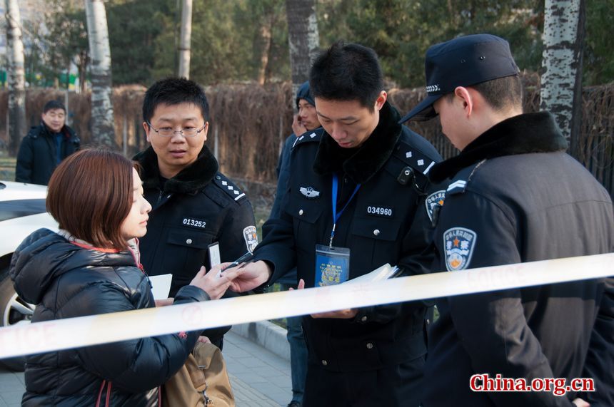 A police officer registers a female reporter who wishes to enter the journalists' zone outside the DPRK embassy in Beijing on Monday, December 19, 2011, amid the news that Kim Jong Il, DPRK's top leader has died. [Maverick Chen / China.org.cn]