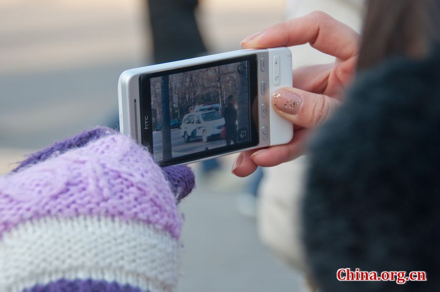 A reporter uses her Android phone to capture images of the DPRK embassy in Beijing on Monday, December 19, 2011, amid the news that Kim Jong Il, DPRK's top leader has died. [Maverick Chen / China.org.cn]